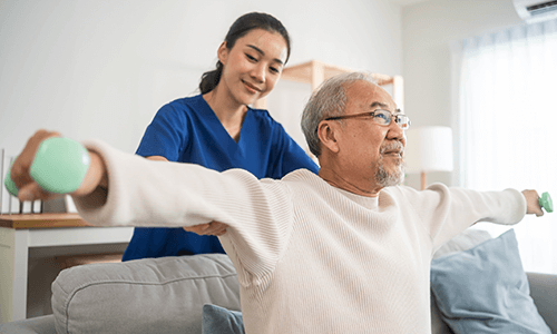 A physiotherapist helps an elderly man stretch.